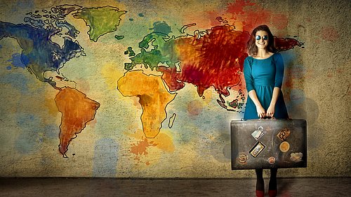 Junge Frau mit großem Koffer vor einer farbigen Weltkarte